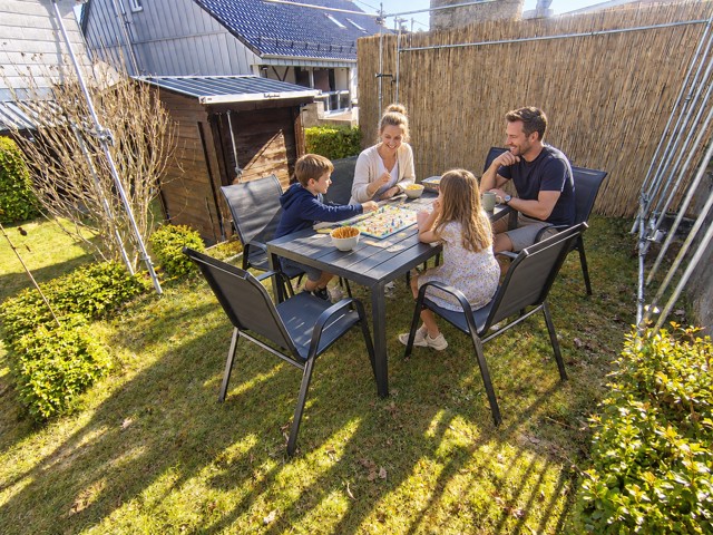Familie spielt am Tisch der Gartensitzgruppe